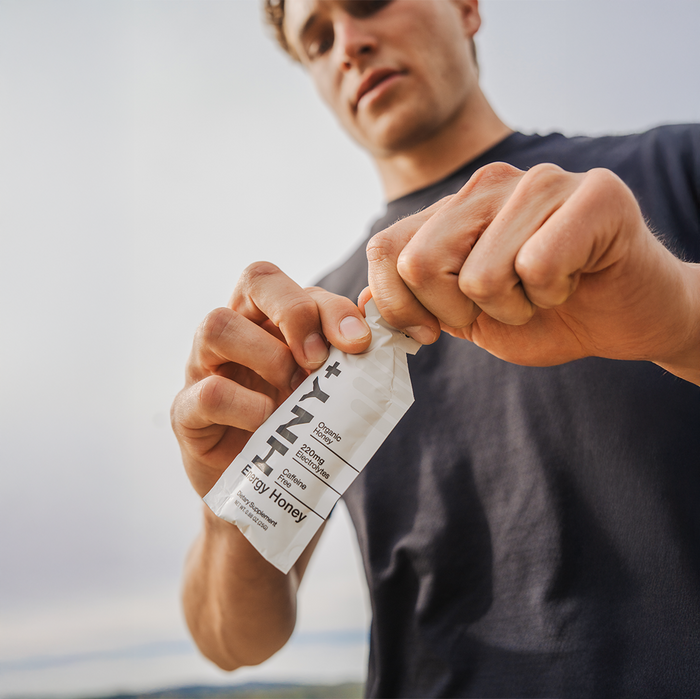 Athlete tearing open an HNY+ Classic energy honey gel